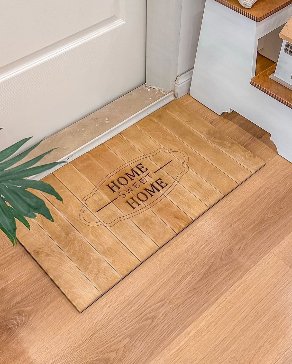 32 Mini Wood Projects for Beginners and Scrap Wood 13 Wooden doormat with Home Sweet Home engraving placed on a light wood floor.