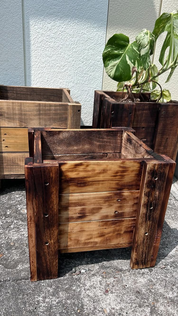 32 Mini Wood Projects for Beginners and Scrap Wood 5 Three dark stained wooden planter boxes, one containing a green leafy plant.