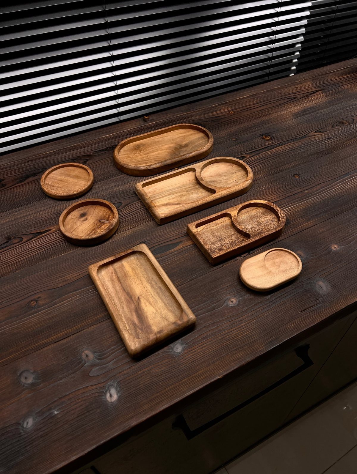 32 Mini Wood Projects for Beginners and Scrap Wood 14 Small wooden serving trays and bowls of various shapes on a dark wood table.