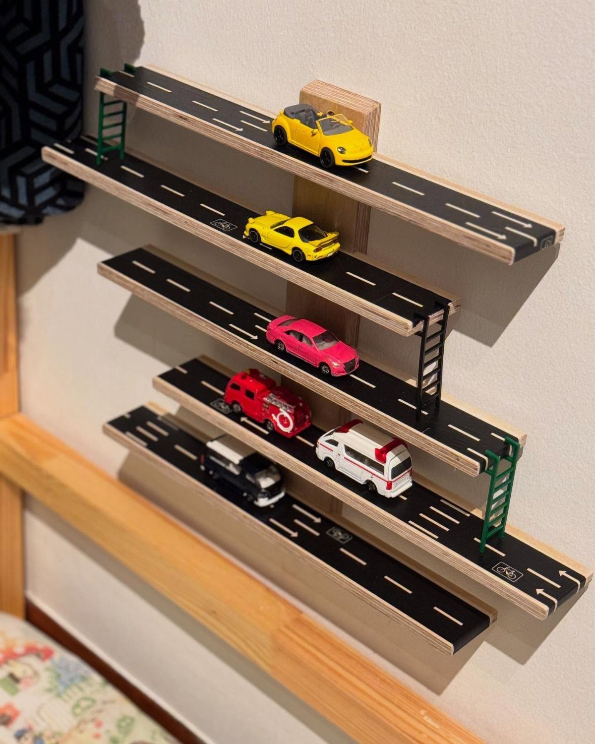 32 Mini Wood Projects for Beginners and Scrap Wood 31 Wooden wall-mounted toy car garage with multiple road shelves and colorful toy cars.