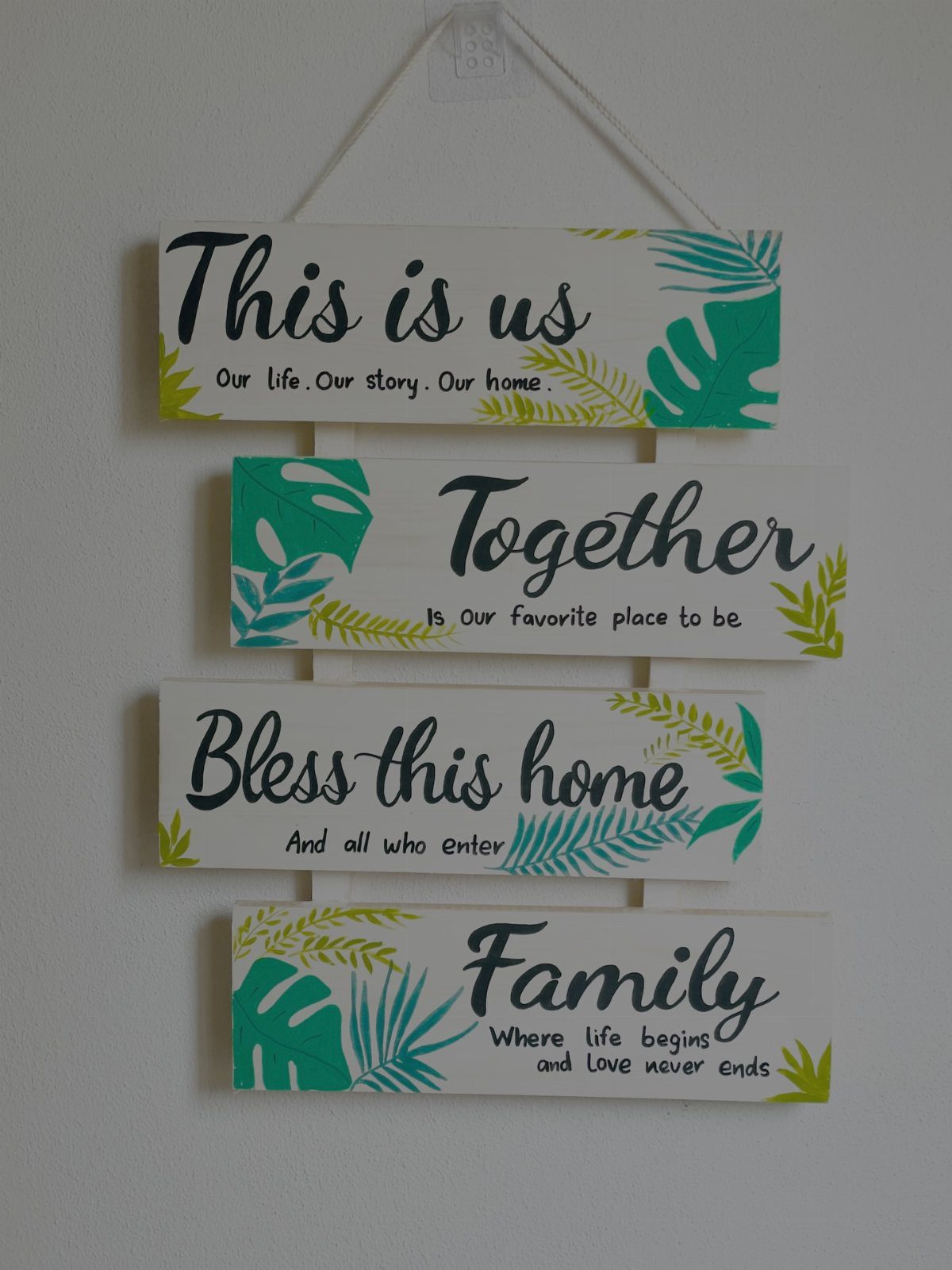 21 Pallet Wood DIY Projects for Home, Holidays and Yard 10 Wooden farmhouse sign with four white planks featuring family quotes and green leaves.