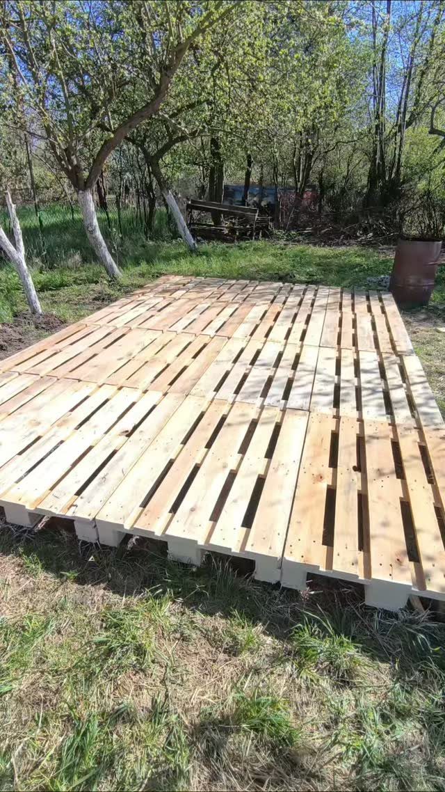 21 Pallet Wood DIY Projects for Home, Holidays and Yard 18 Wooden pallet platform laid on grass in a garden with trees behind it