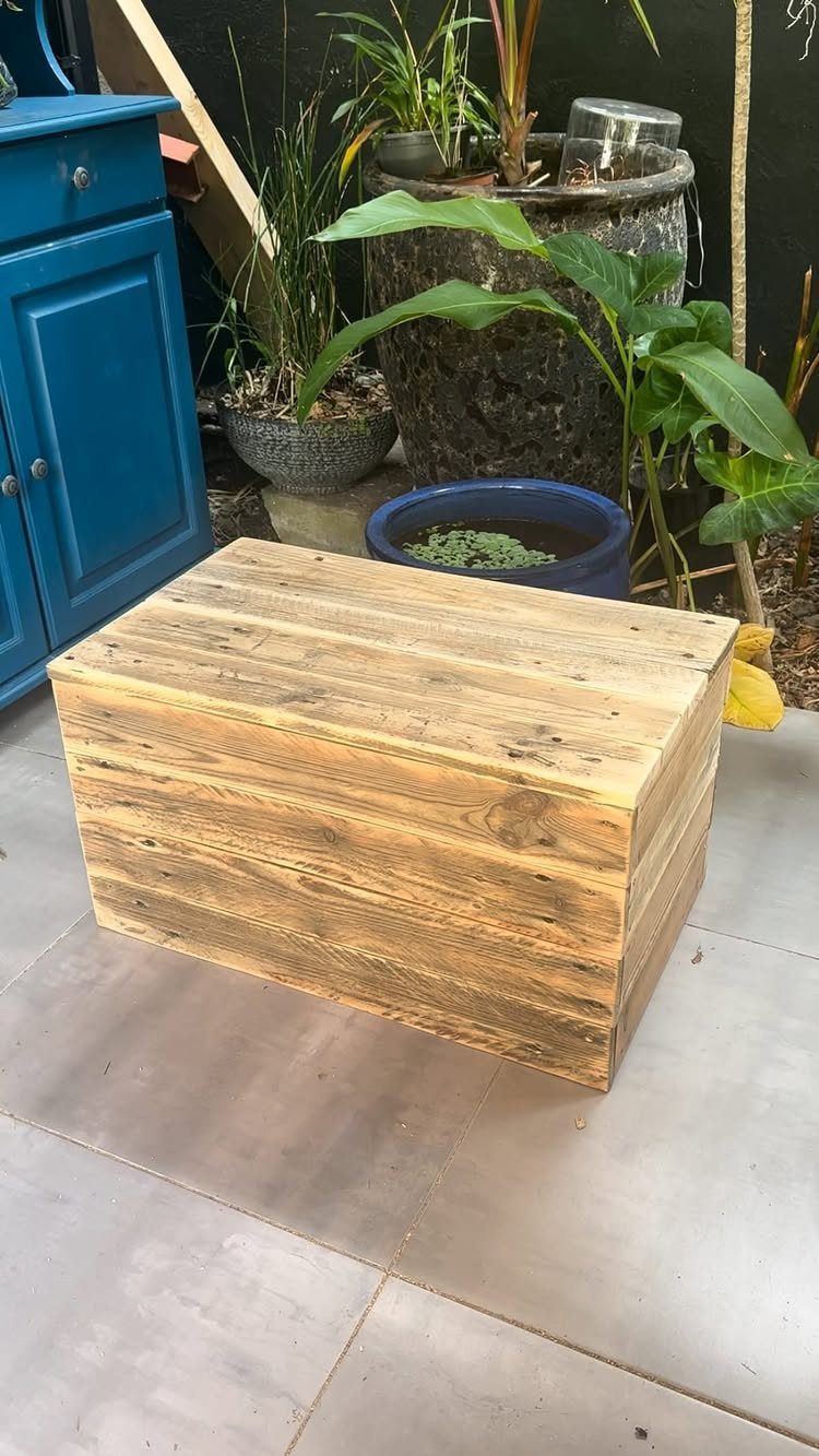 21 Pallet Wood DIY Projects for Home, Holidays and Yard 20 Wooden pallet box sitting on a grey tiled floor next to potted plants.