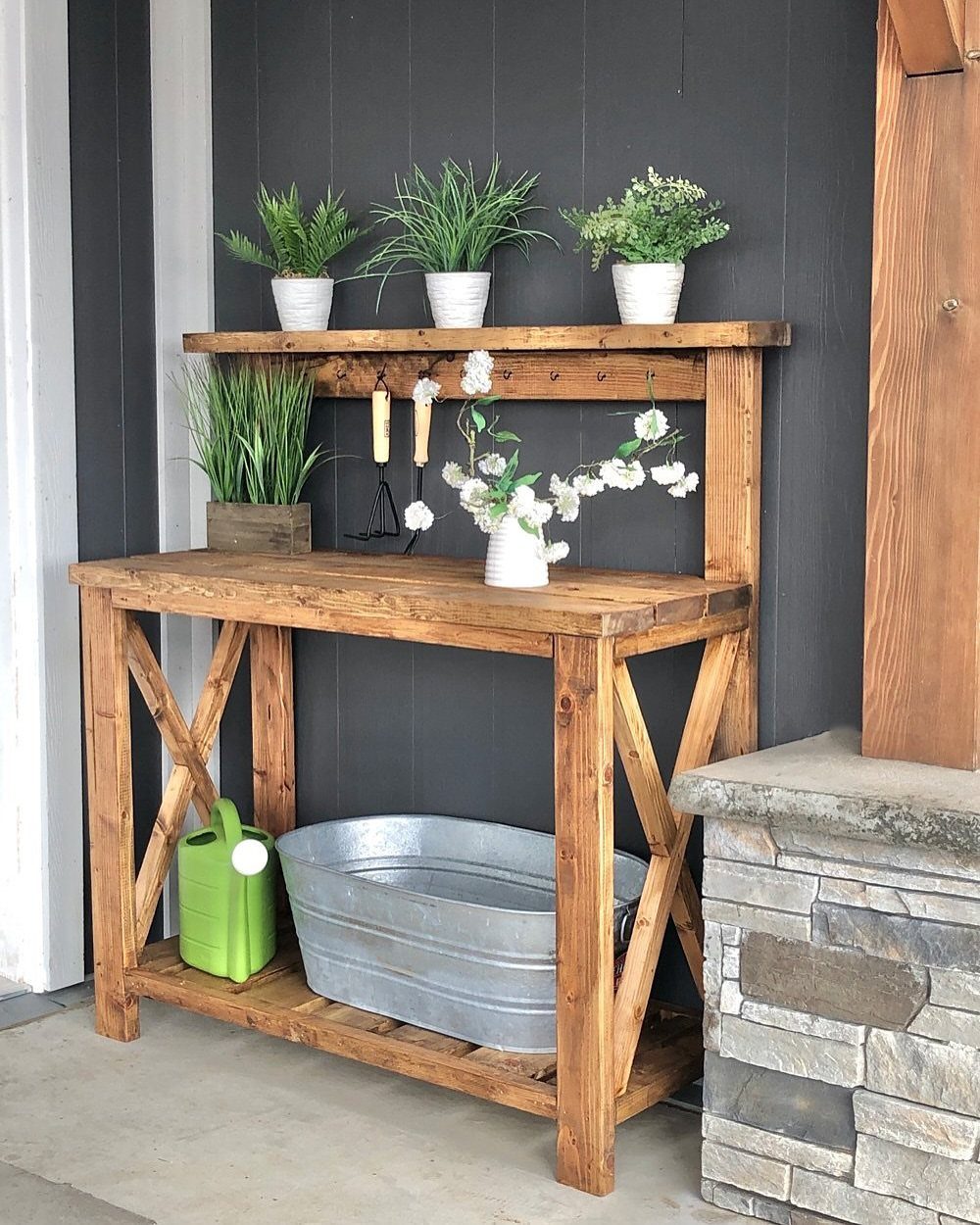 Wooden farmhouse potting bench with upper shelf, slatted bottom shelf, and galvanized tub.