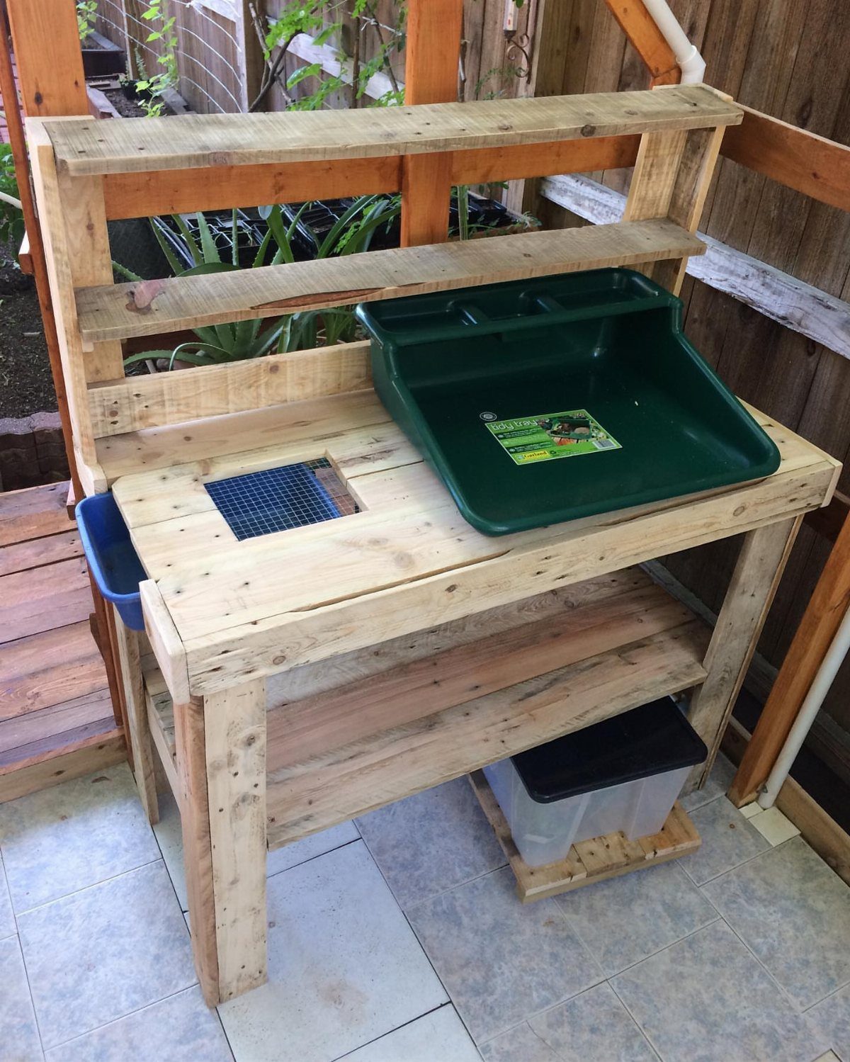 Wooden potting bench with a hutch, green sink, and lower storage shelf.