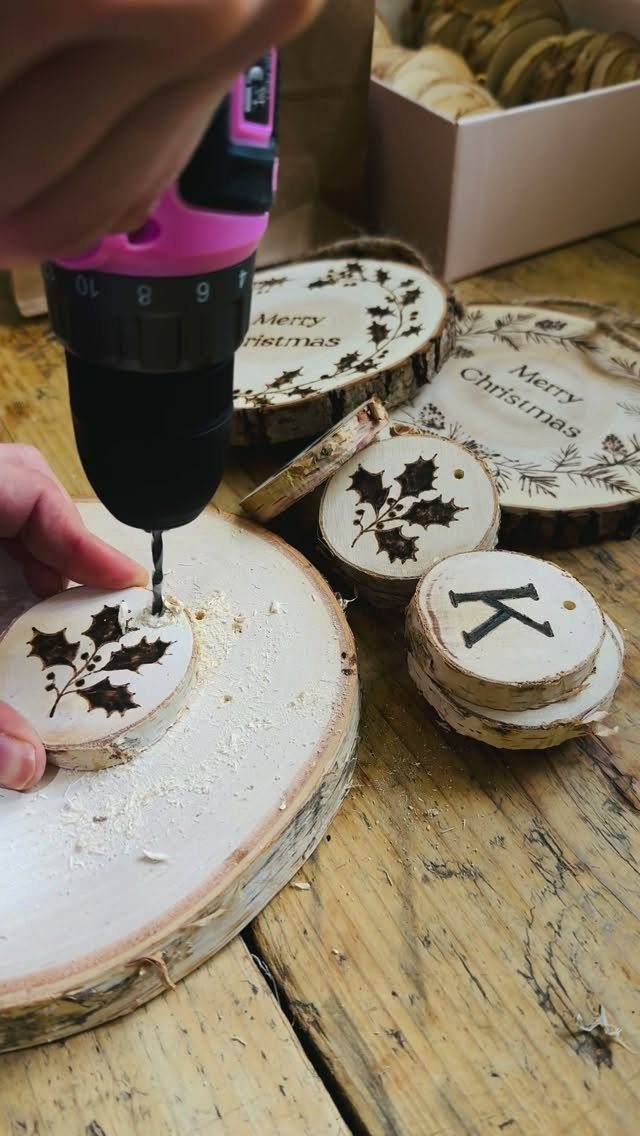 Pyrography Patterns Free to Try: 6 Wood Burning Ideas 3 Hand drilling a hole in a wood slice with a wood-burned letter K nearby.