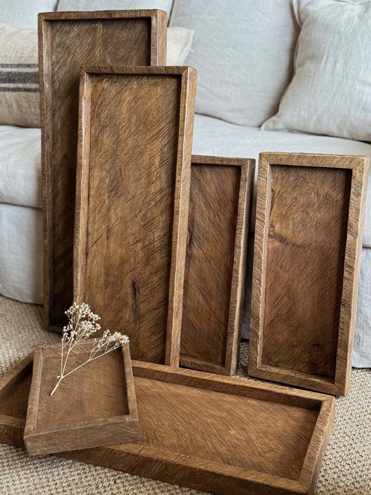 14 Reclaimed Wood Projects for Rustic Home Decor 12 Wooden serving trays of different sizes leaning against a white sofa on carpet.
