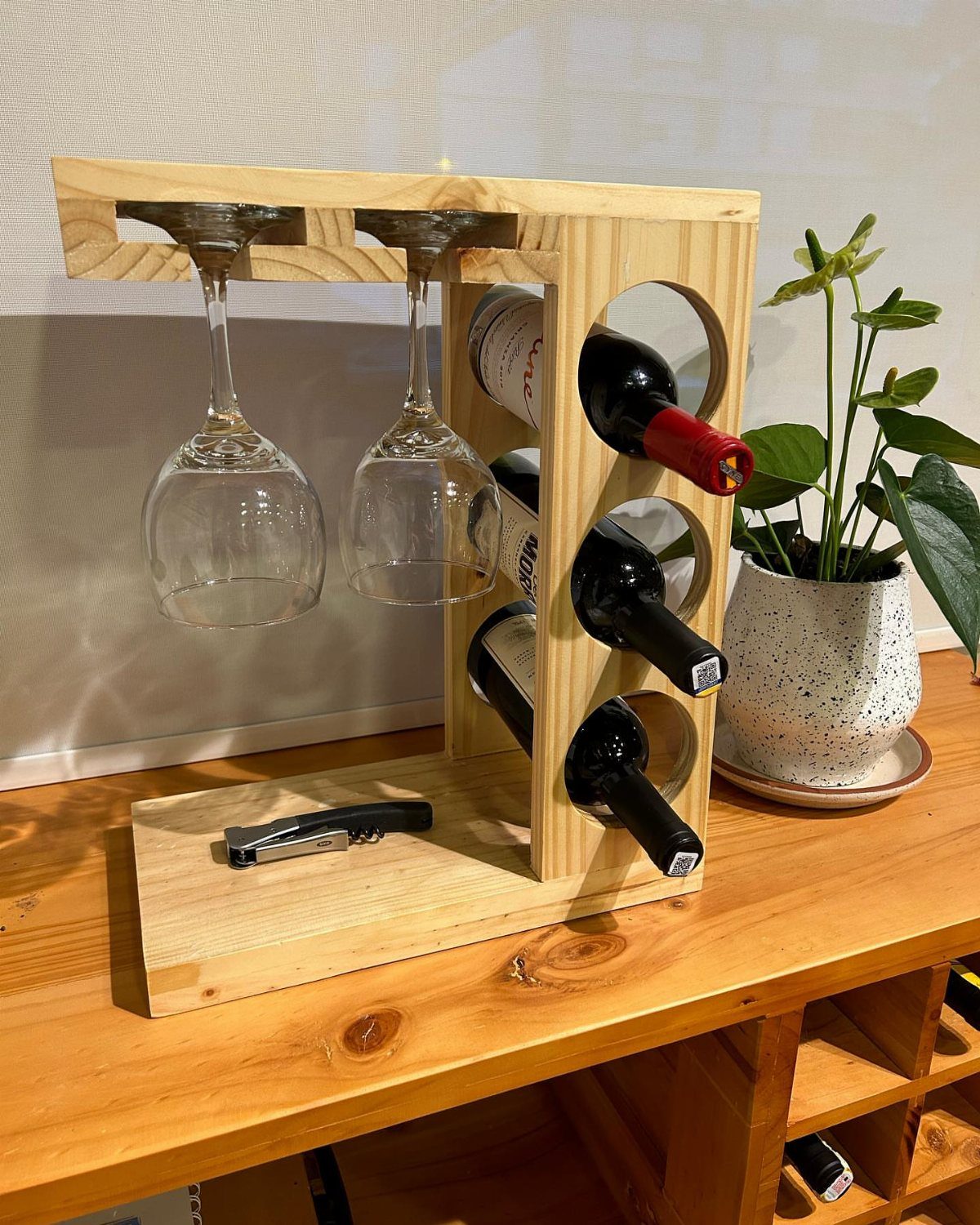 14 Reclaimed Wood Projects for Rustic Home Decor 10 Wooden wine rack holding wine bottles and hanging glasses on a table.