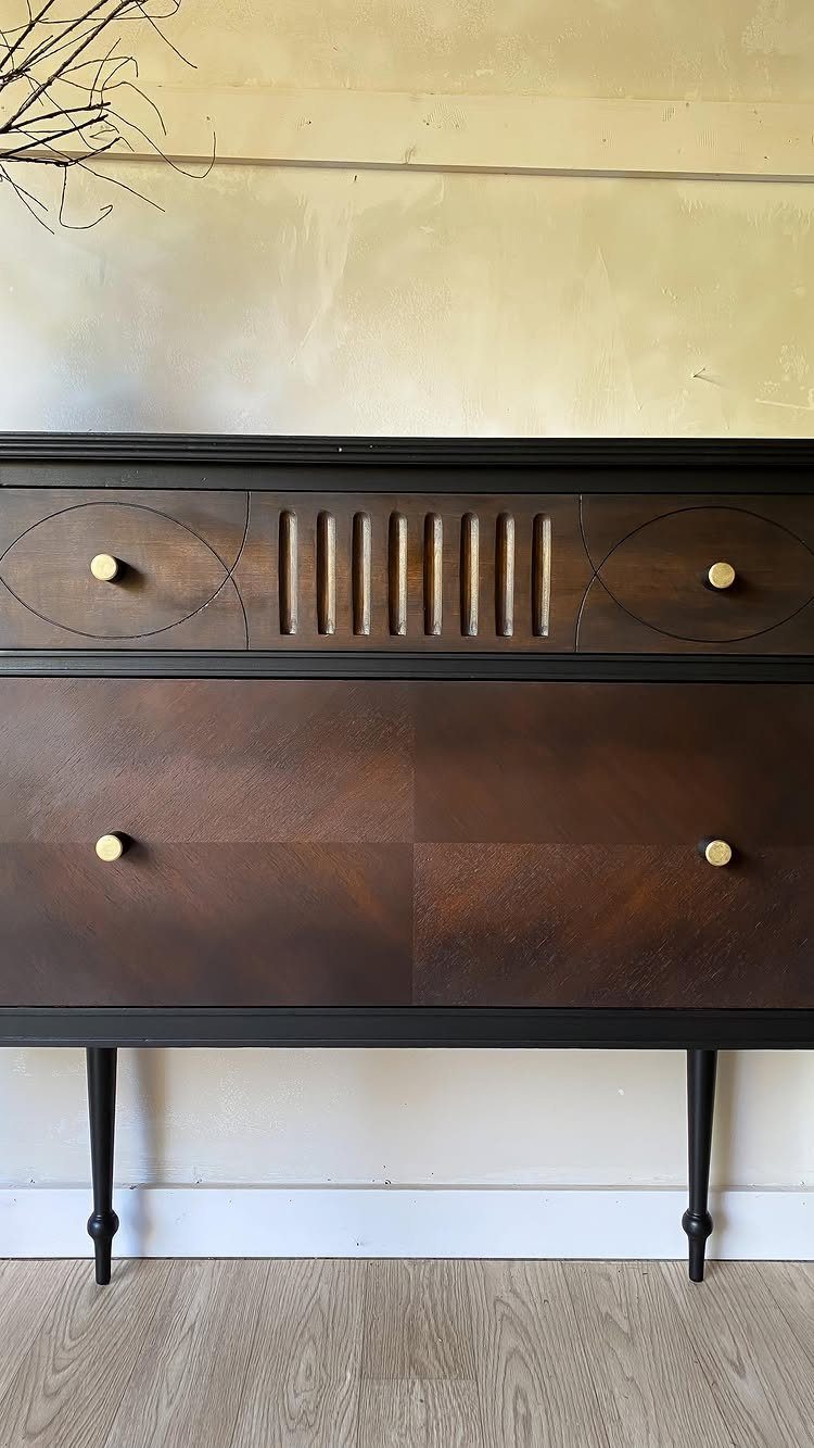 Mid-century modern wooden sideboard with dark brown stain and black legs against a wall.