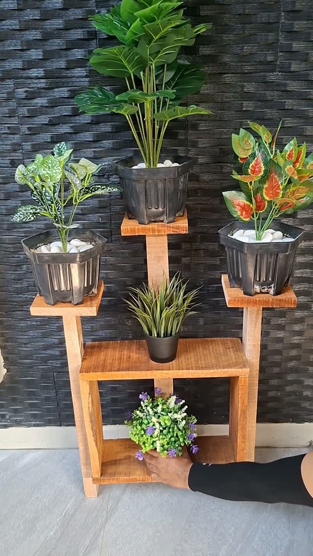 Rustic Plant Stand Ideas: 5 Styles for Any Room 1 Multi-level wooden plant stand holding several potted green plants against a dark wall.