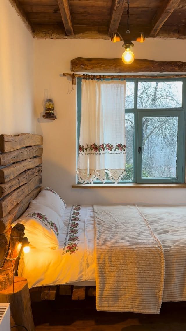 Rustic log headboard on a bed in a cozy room with wooden ceilings.