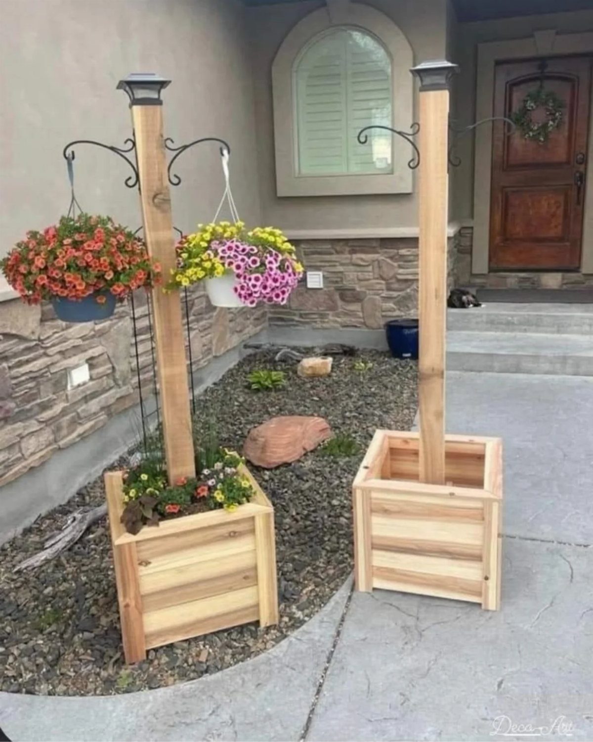 Wooden planter boxes with tall posts and hanging flower baskets by a house.