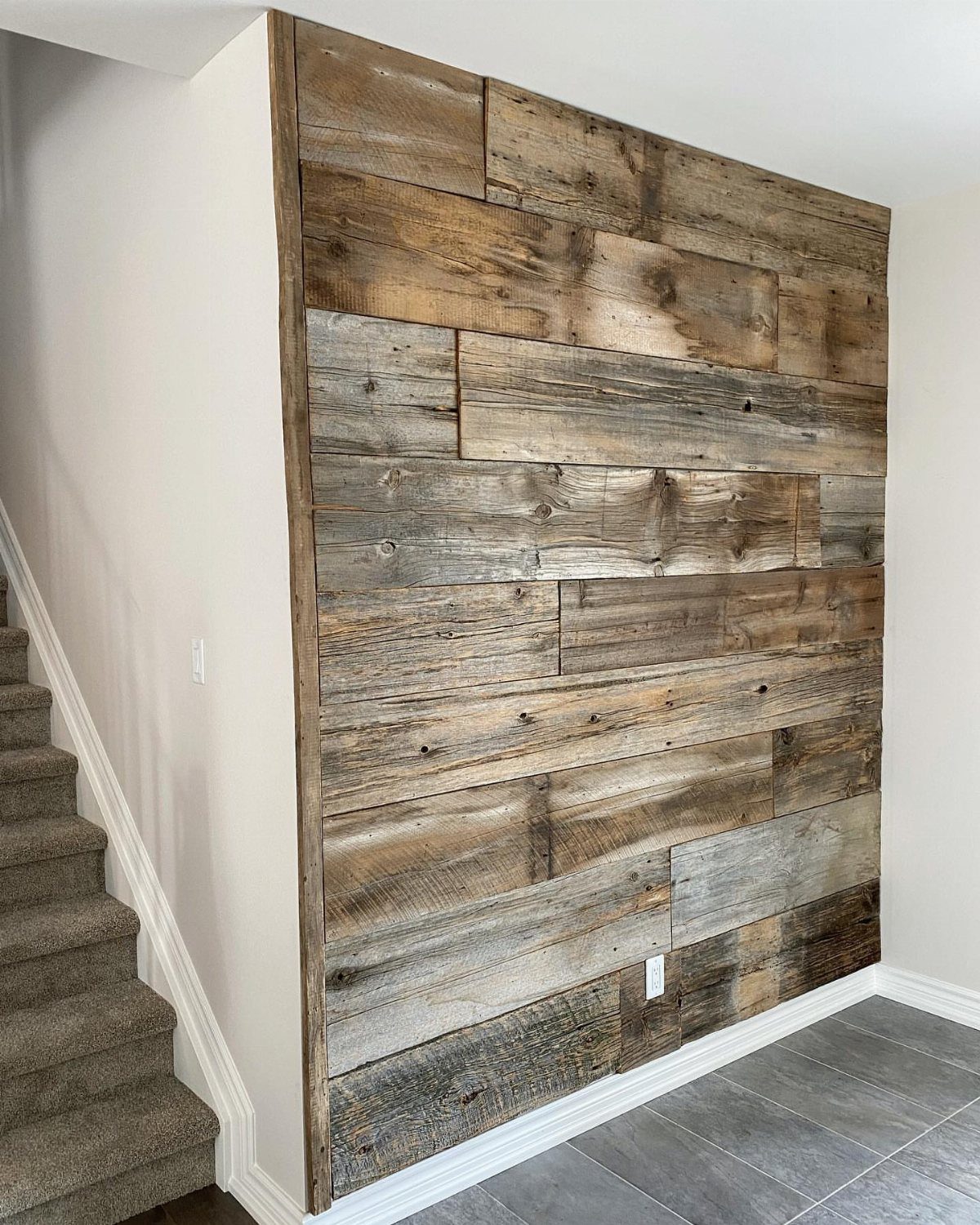 Reclaimed wood wall planks in brown and grey tones next to a staircase.