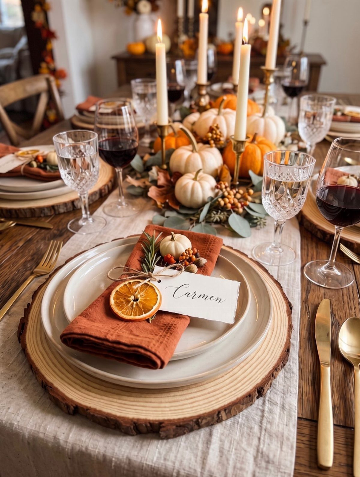 Rustic table centerpiece with pumpkins, candles, and greenery on a wooden dining table.
