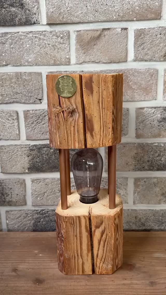 Rustic wood lamp with an exposed light bulb against a brick wall