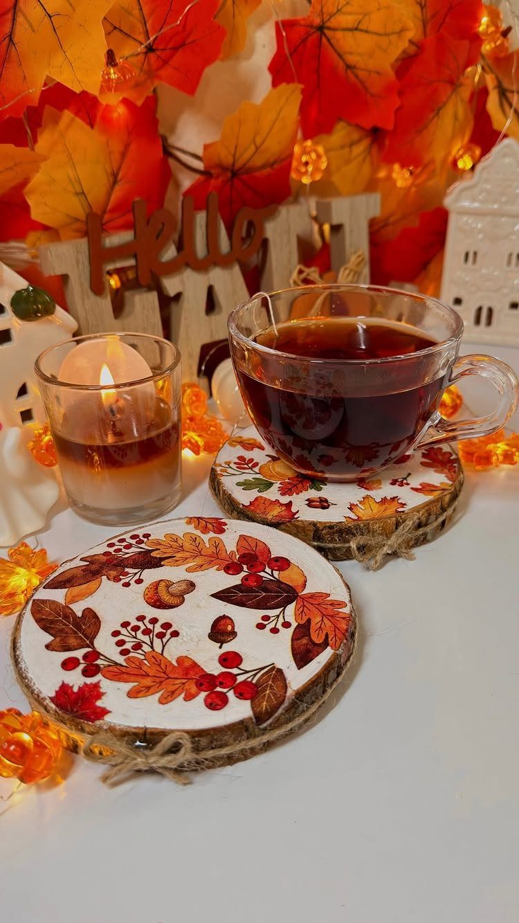 Wood slice coasters with autumn leaf art holding a glass cup of tea.