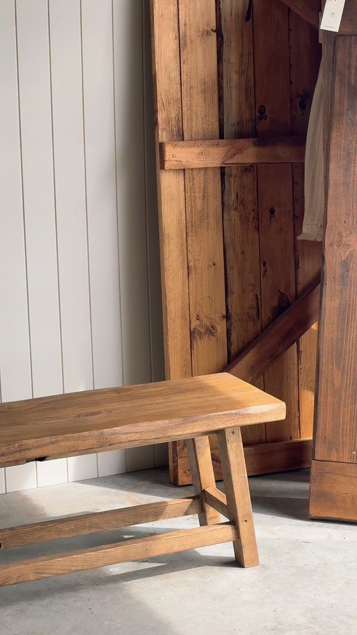Wooden bench with a thick top and A-frame legs against a rustic door.