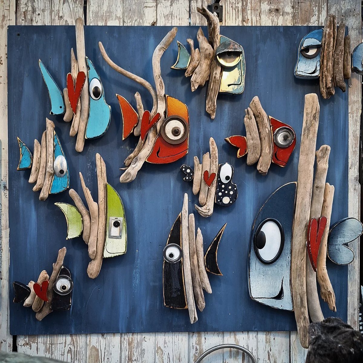 13 Scrap Wood Art Ideas for Using Up Your Leftover Boards 11 Whimsical fish sculptures made from driftwood and painted wood on a blue background.