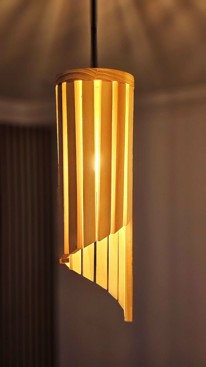 13 Scrap Wood Art Ideas for Using Up Your Leftover Boards 9 Cylindrical wooden slat pendant light with warm yellow glow and asymmetrical bottom edge.