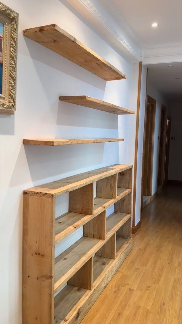 Rustic reclaimed wood floating shelves and a low shelving unit on a white wall.