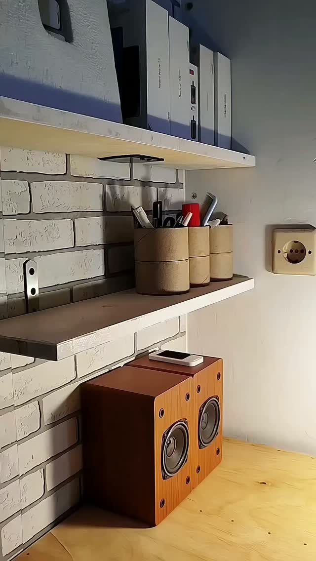Wooden wall shelves on a white brick wall holding binders and pen holders.