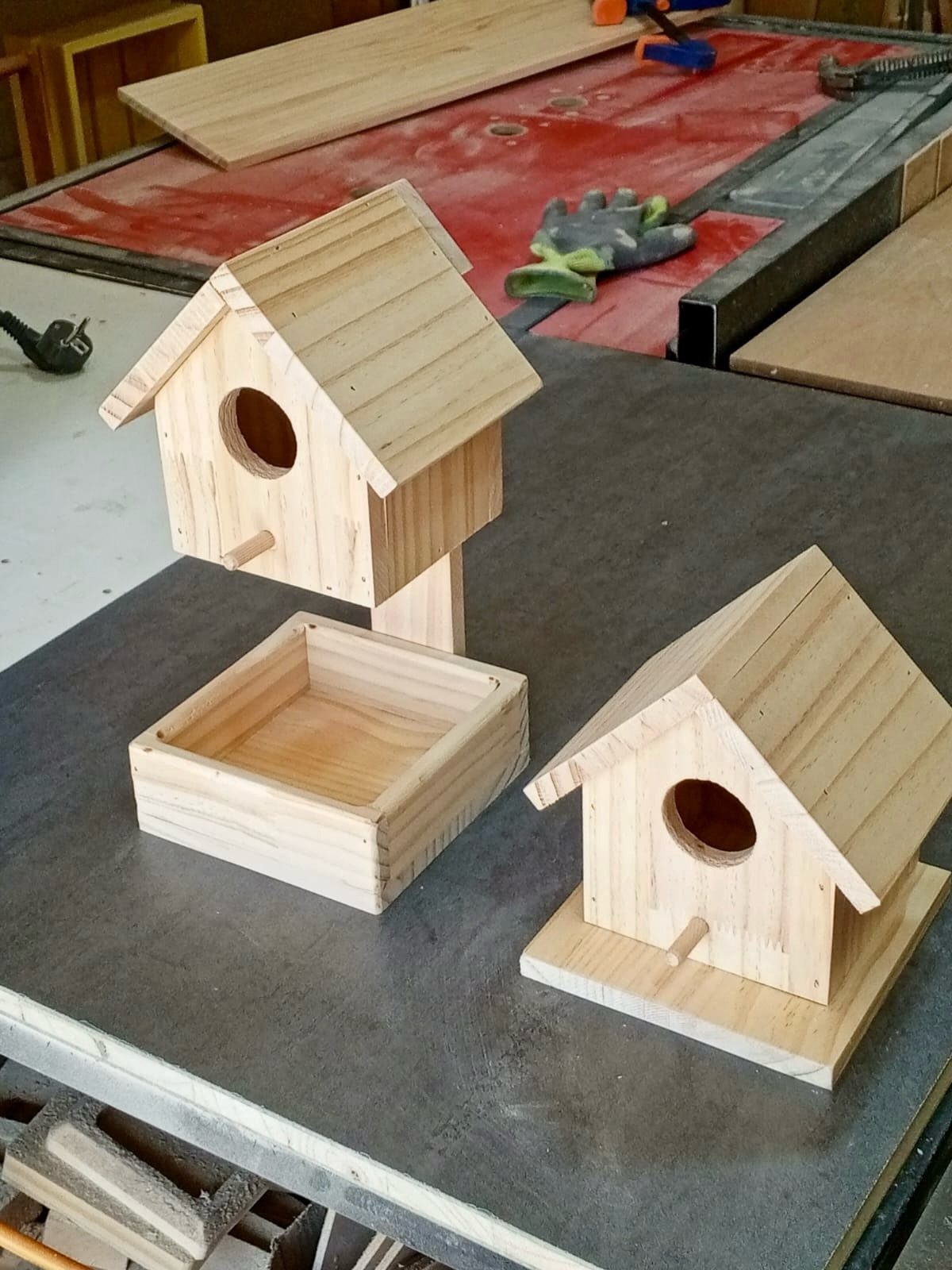 13 Small Wood Craft Ideas for Beginners and Scrap Wood 2 Two unfinished wooden birdhouses and a small tray on a dark workshop table.
