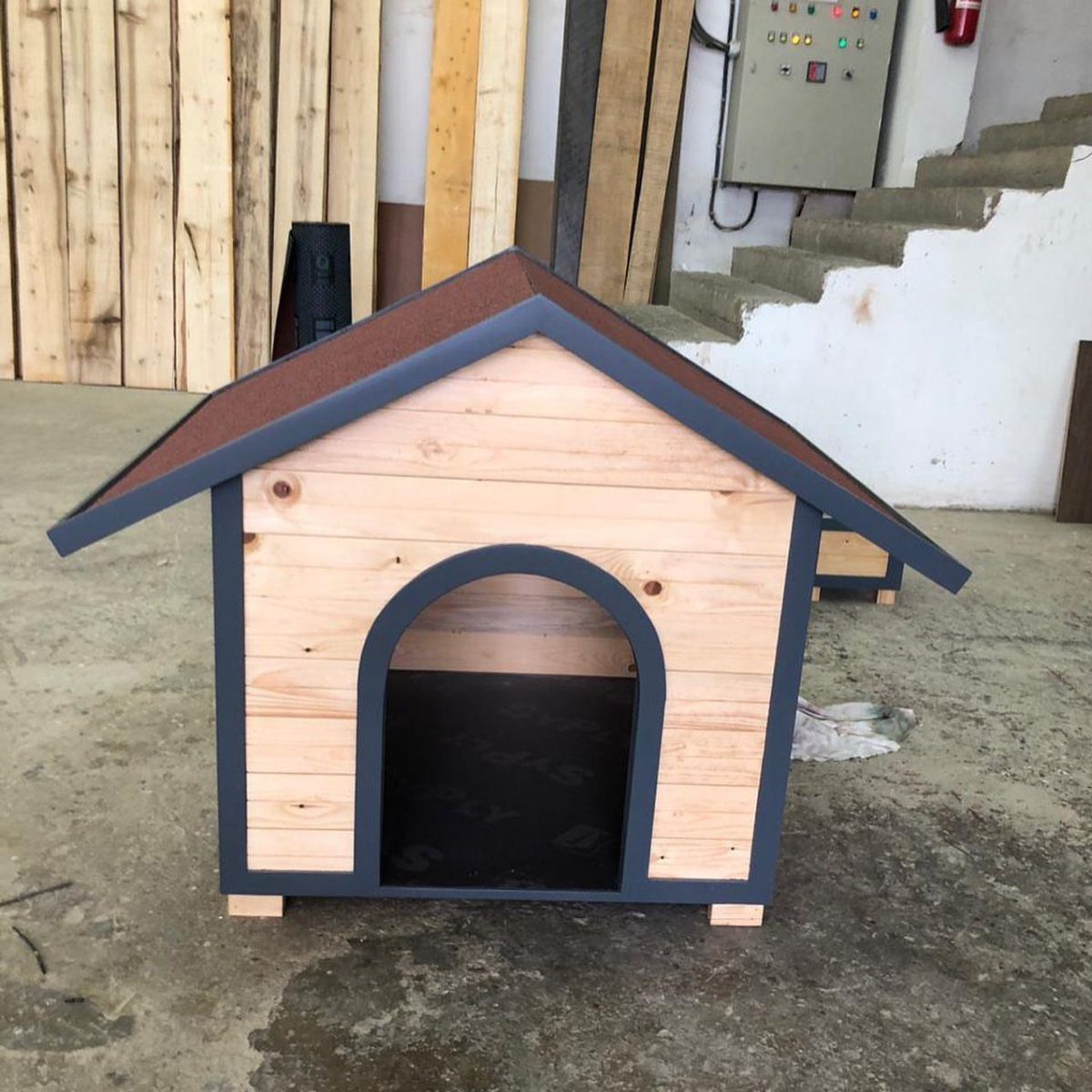 13 Small Wood Craft Ideas for Beginners and Scrap Wood 12 Wooden dog house with dark grey trim and brown roof in a workshop.
