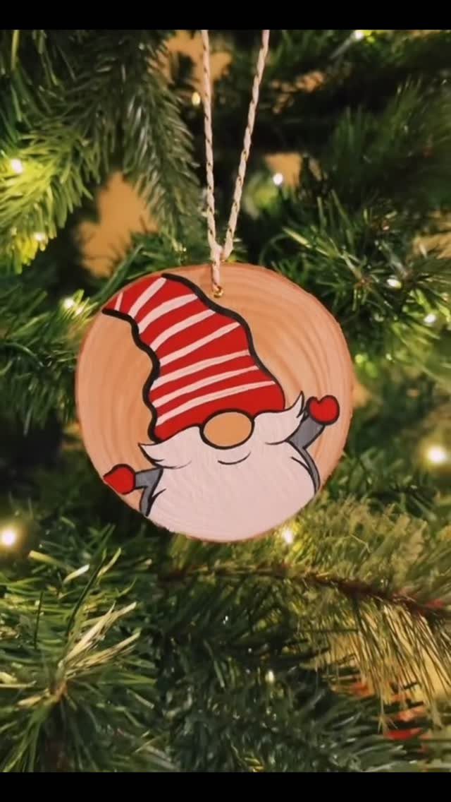 21 Small Wood Projects for Christmas You Can Make 1 Wooden circular ornament painted with a gnome hanging on a lit Christmas tree.