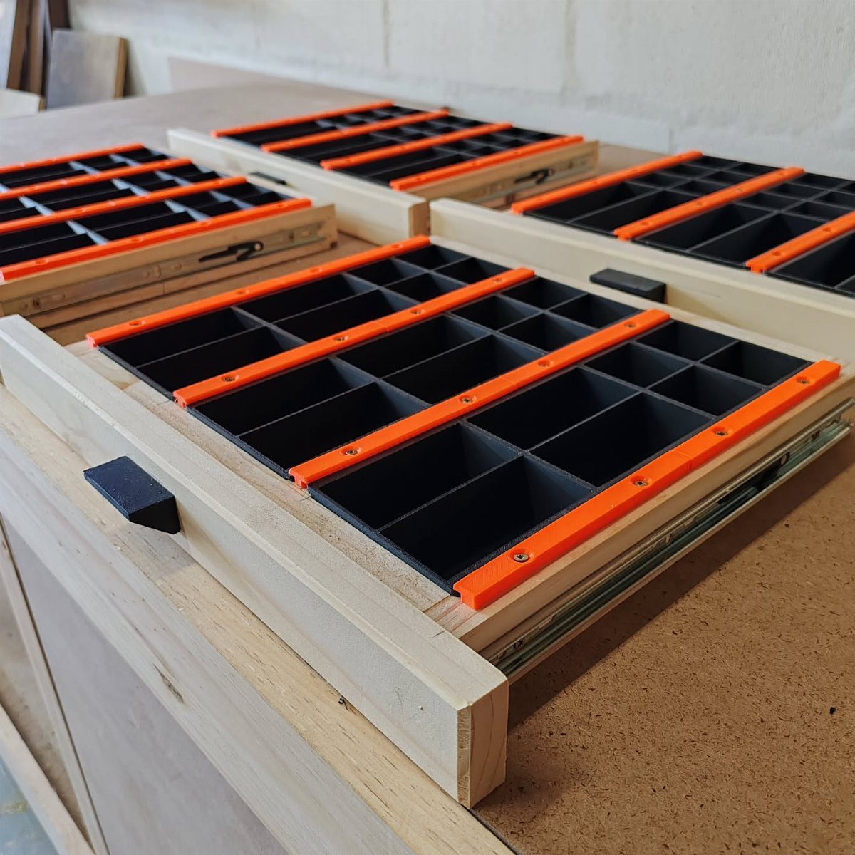12 Small Workshop Storage Ideas for Tight Spaces 1 Wooden drawers with black foam and orange dividers for organizing small workshop tools.