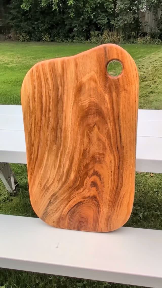 24 Summer Wood Projects for Beginners and Weekend Builders 11 Wooden cutting board with natural grain leaning on a white outdoor table.