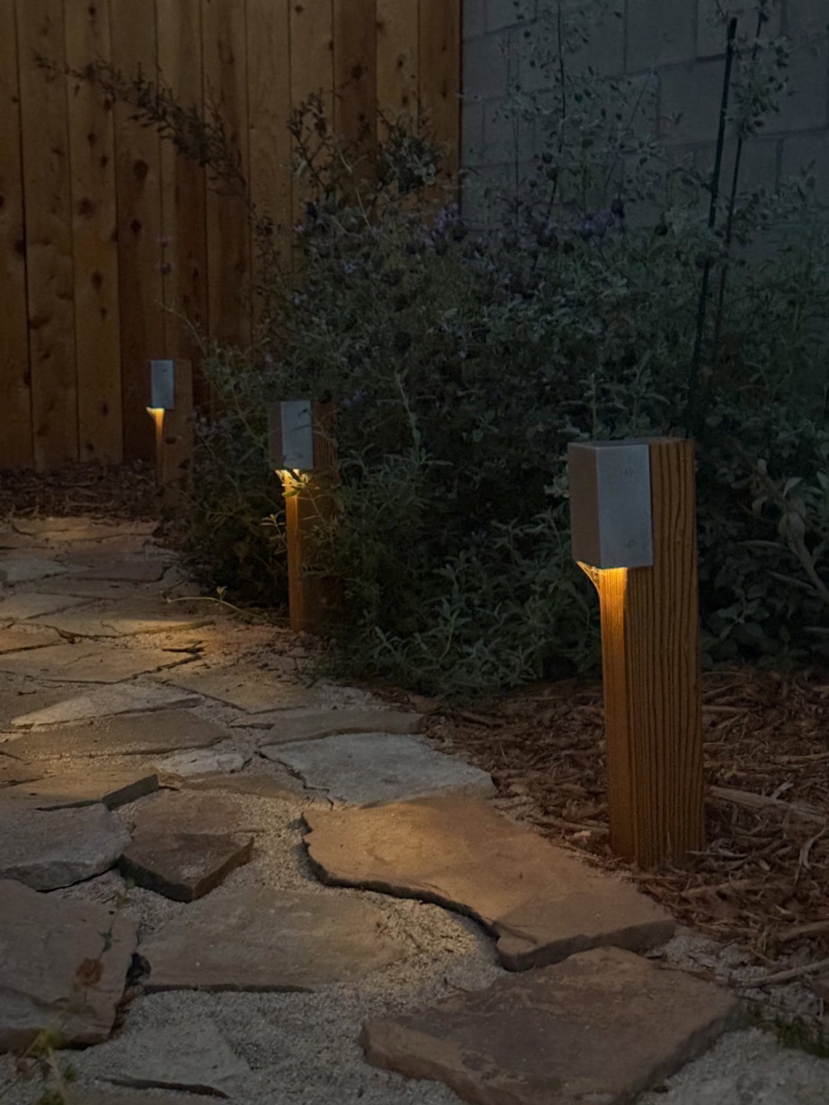 24 Summer Wood Projects for Beginners and Weekend Builders 19 Wooden solar light stands illuminating a stone garden path at dusk