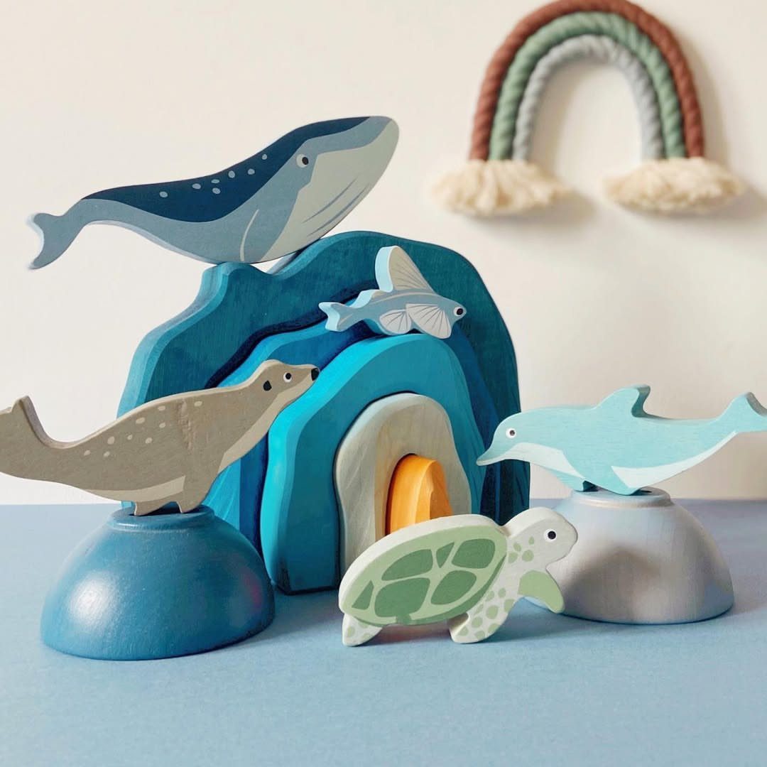 24 Summer Wood Projects for Beginners and Weekend Builders 23 Painted wooden sea animal toys arranged around a blue wooden wave structure.