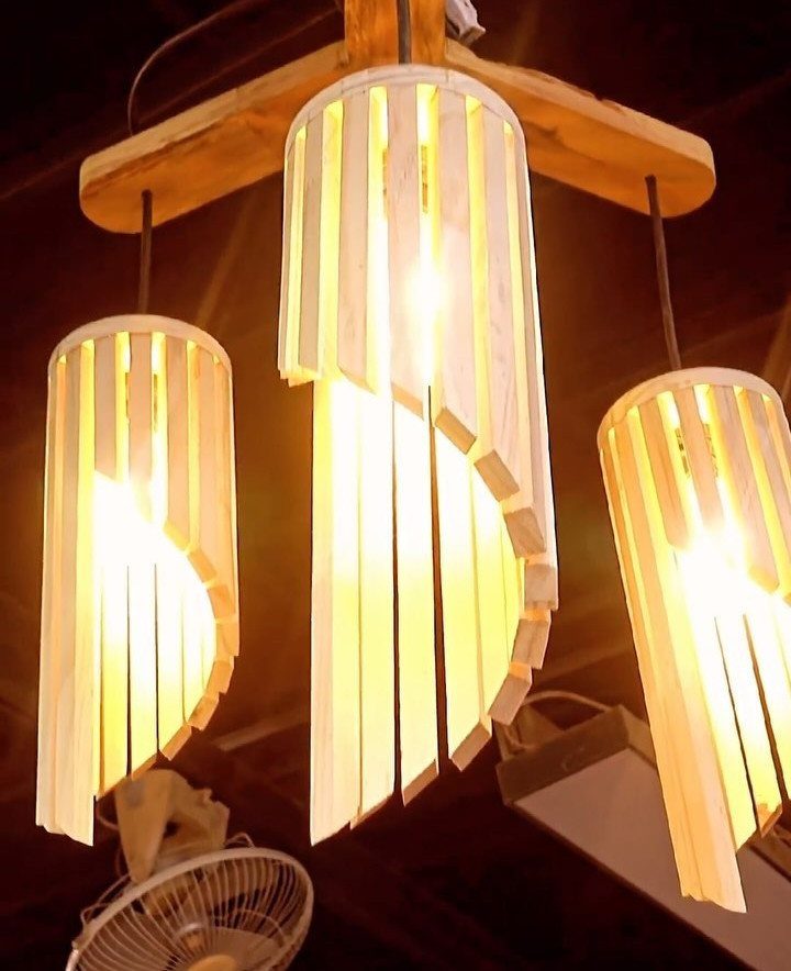 Three cylindrical wooden slat pendant lights glowing with warm yellow light.