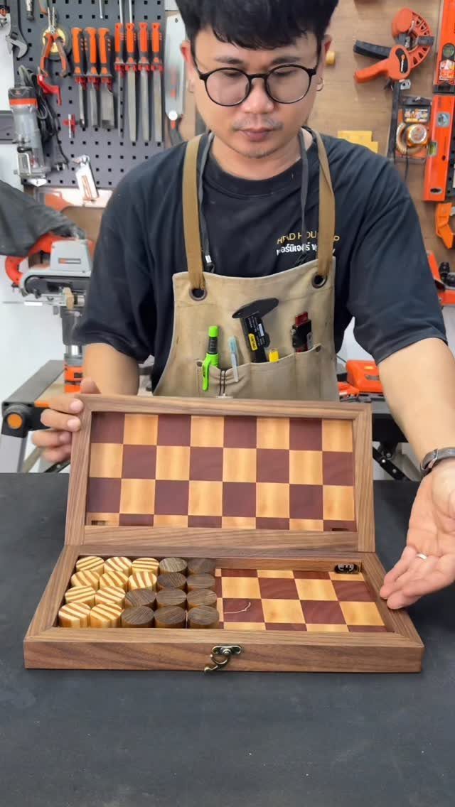 Man in workshop holding a handcrafted wooden checkered game board in a box