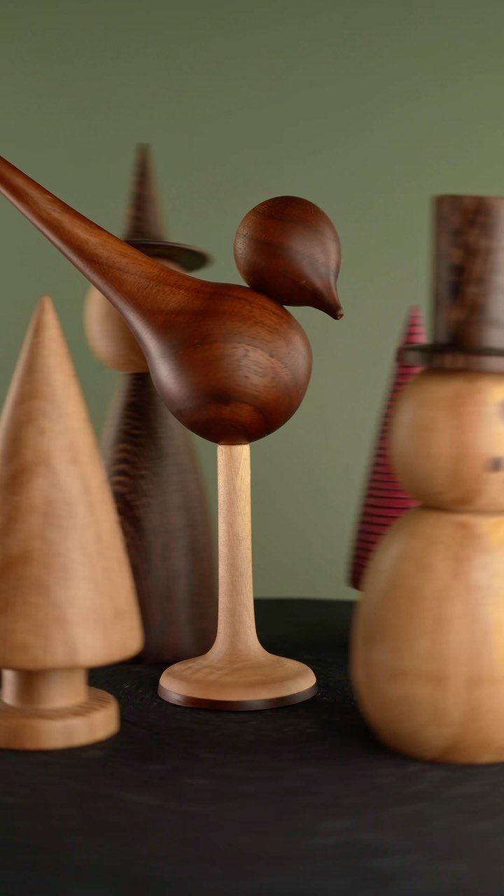 Carved wooden bird and other stylized wooden figurines on a dark surface.