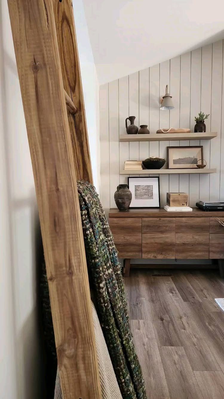 Wooden blanket ladder leaning against a wall with a patterned throw blanket draped over it.