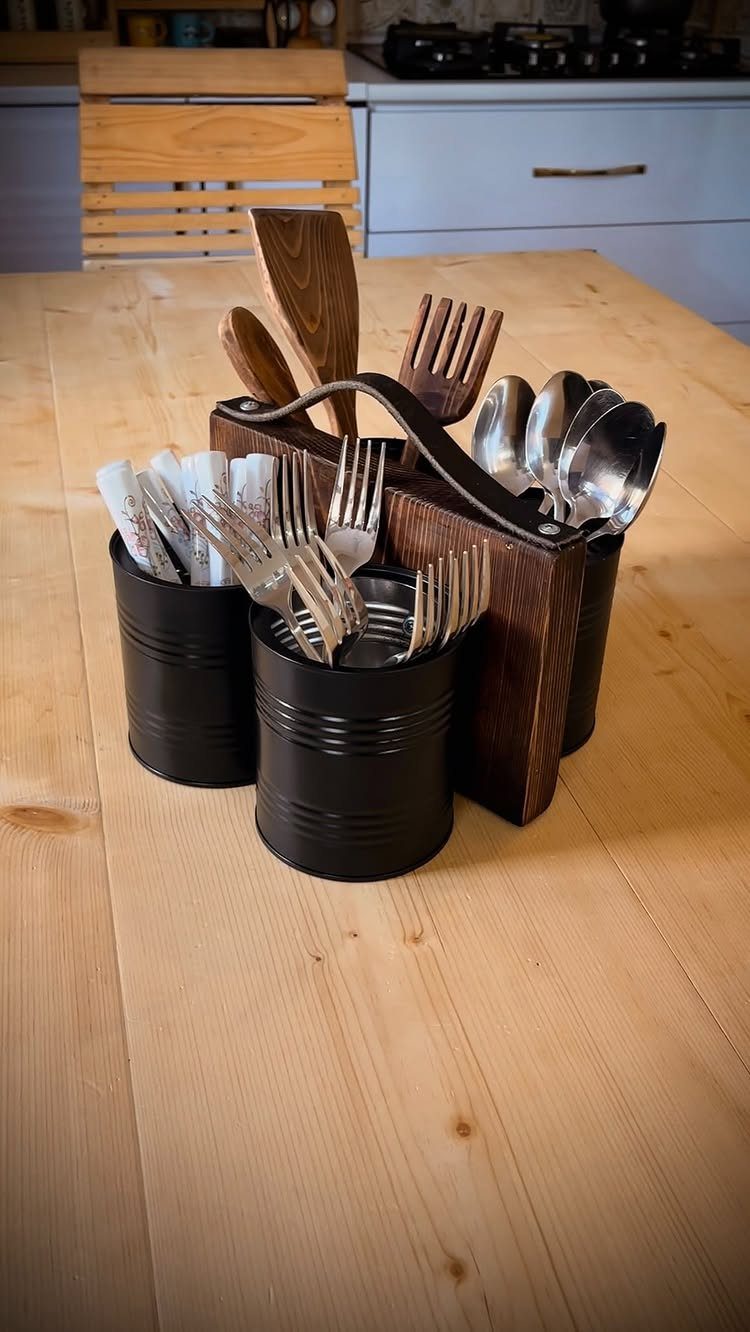 Wooden utensil holder with black canisters containing forks, spoons, and wooden kitchen tools.
