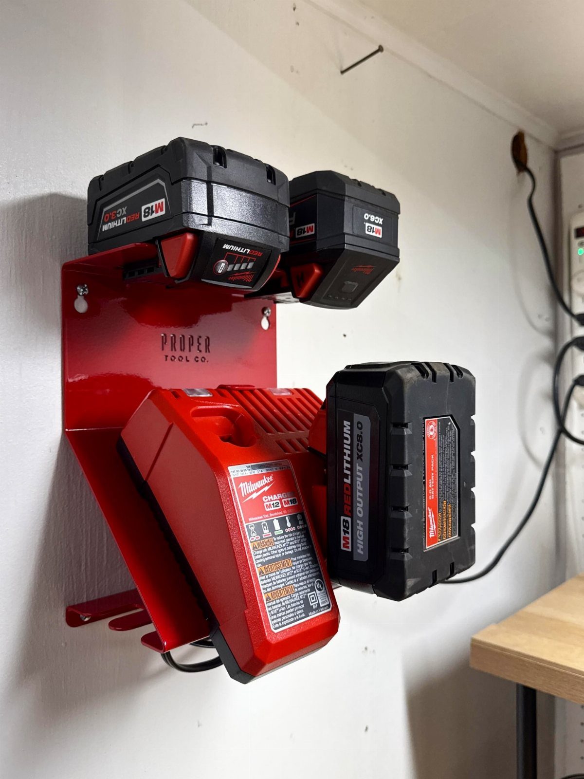 Tool Storage DIY Ideas: 7 Projects for Any Garage 3 Red wall-mounted charging station holding several black and red power tool batteries.