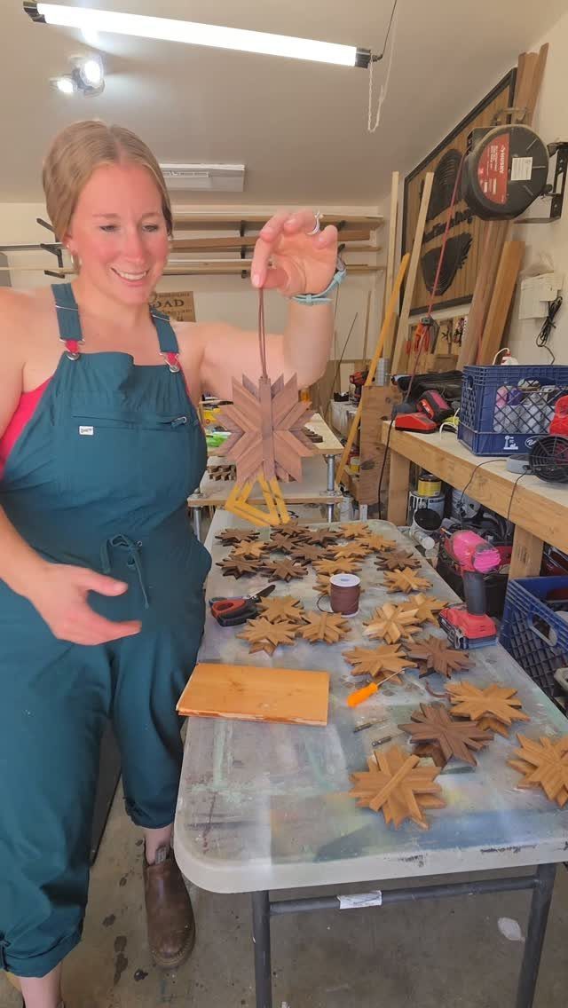 Woman holding a carved wooden star with many others on a workshop table