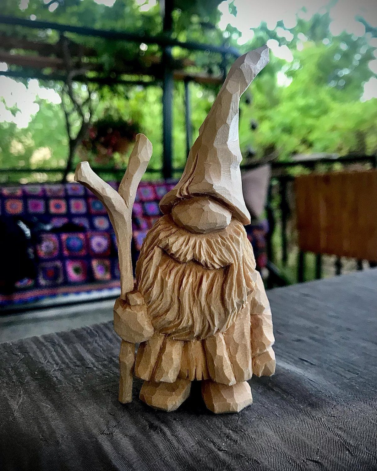 Hand-carved wooden gnome with a long beard and tall hat holding a staff.