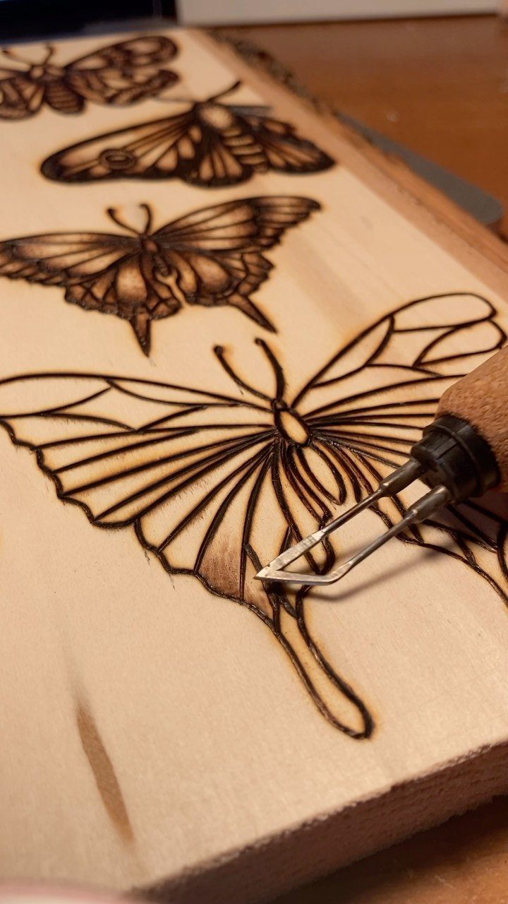 12 Wood Burn Designs for Beginners: Strokes and Patterns 3 Wood burning tool creating thin outlines of butterflies on a light wooden board.