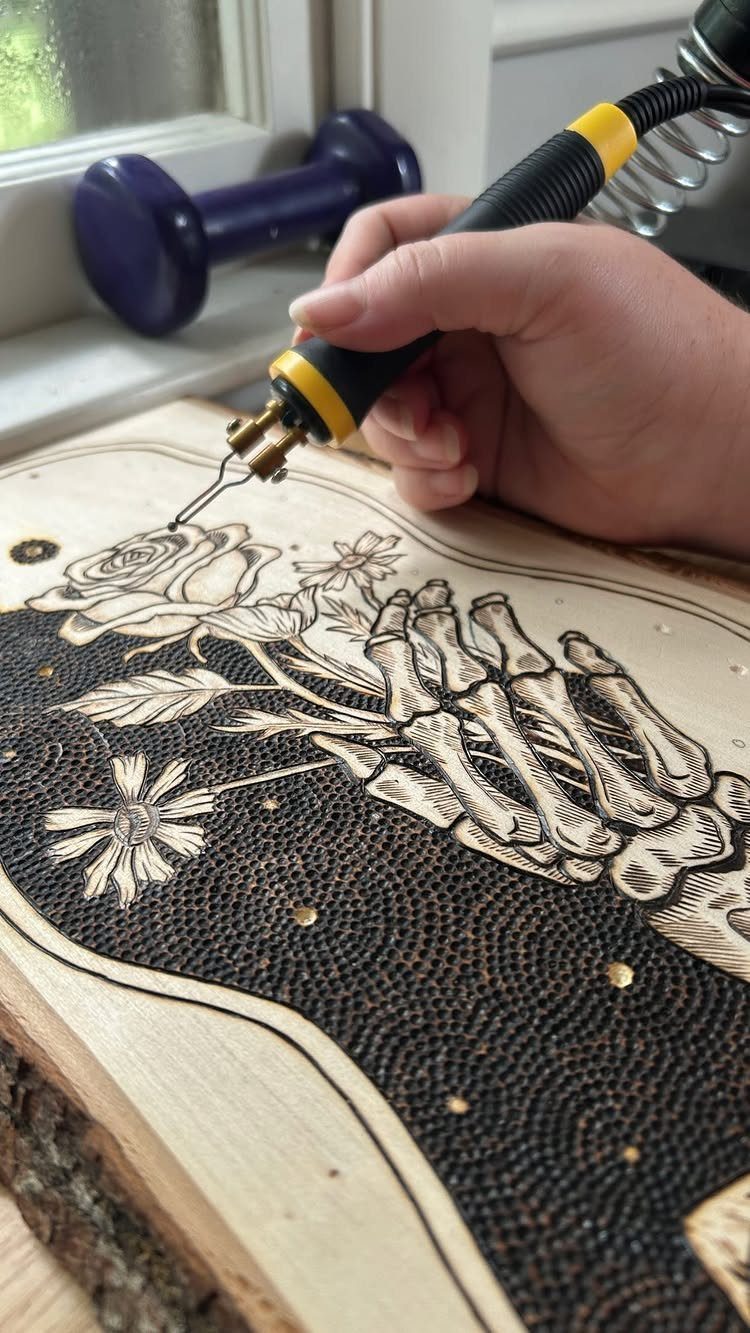 Wood Burning Carving Ideas: 7 Designs for Pyrography 4 Hand using a wood burning tool to carve a skeletal hand and rose.