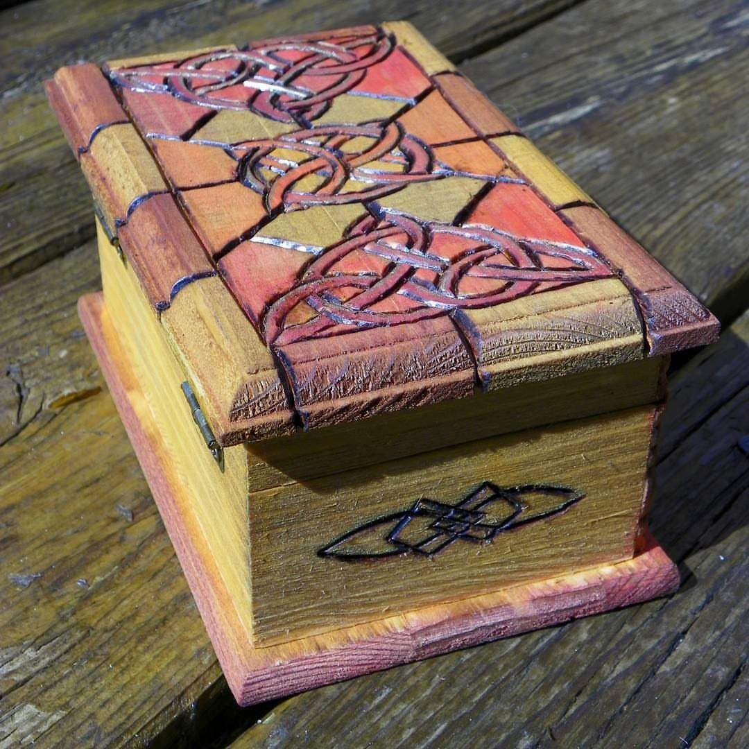 Wooden box with intricate carved Celtic knot designs on the lid and side.