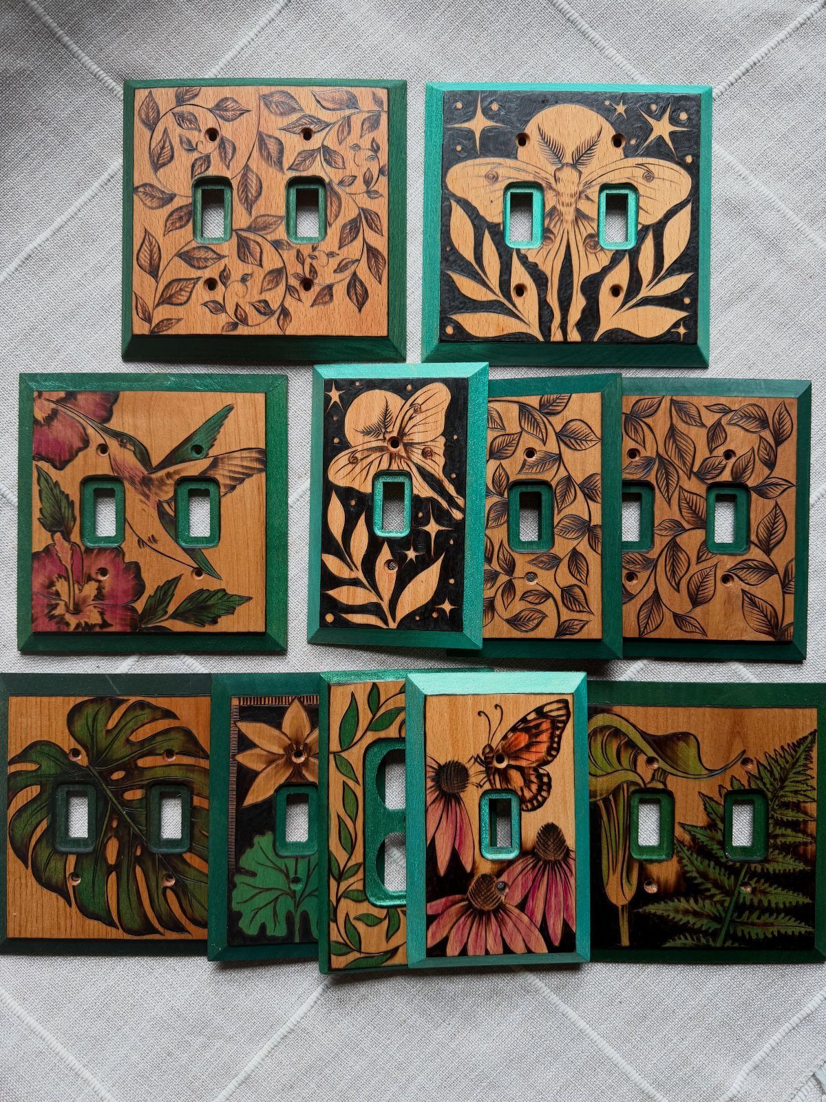 Wooden light switch covers featuring detailed wood-burned botanical and animal illustrations.