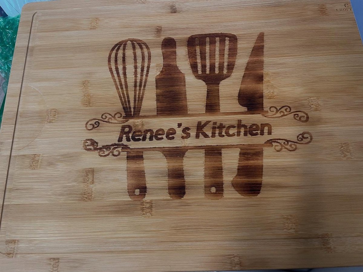 Wooden cutting board with wood-burned kitchen utensils and the text Renee's Kitchen.