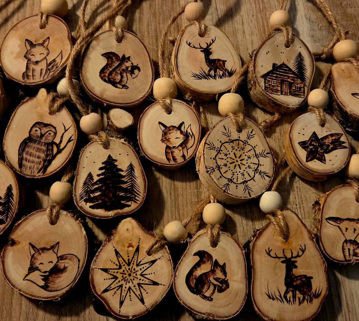 Wooden slices with burned illustrations of foxes, deer, and owls on a wooden table