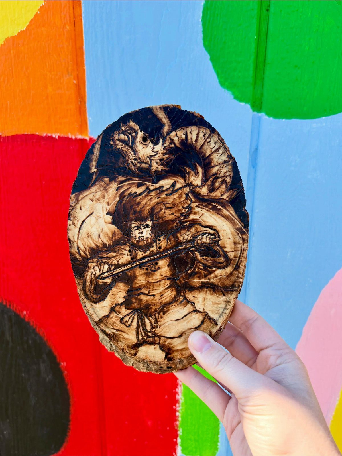 Wood slice with a detailed wood burned illustration of a fantasy battle scene