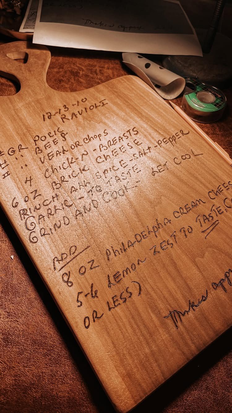 Wooden cutting board with a handwritten ravioli recipe burned into the wood surface