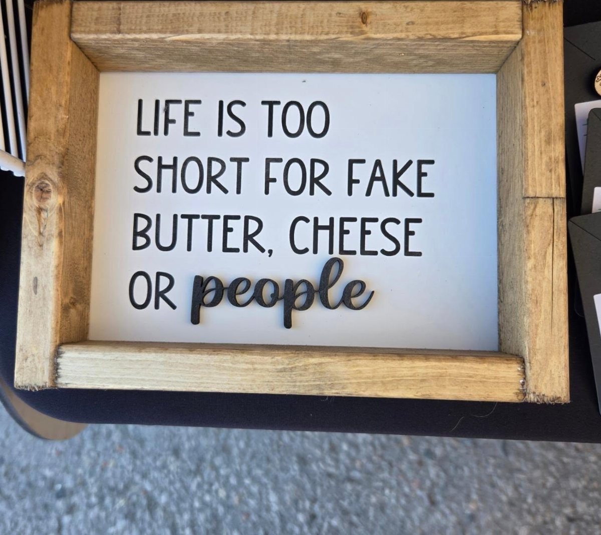 Wooden framed kitchen sign with a humorous quote about butter, cheese, and people.