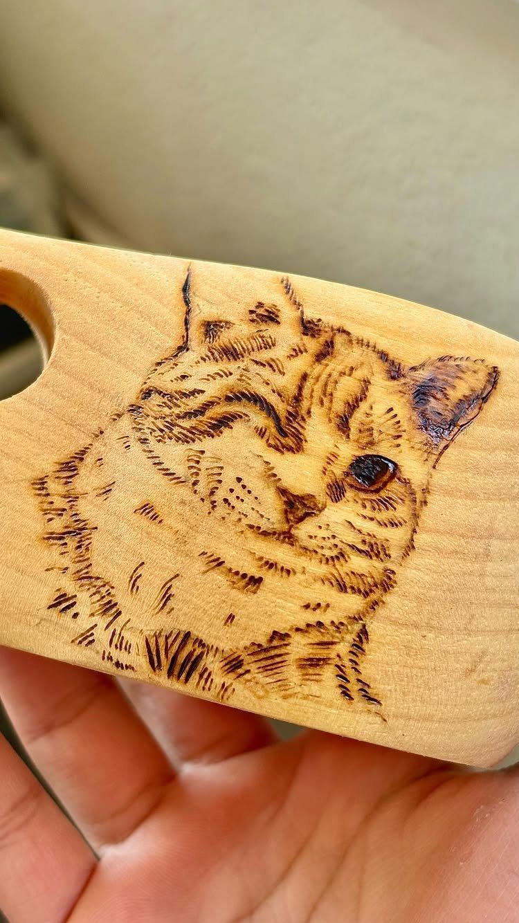 Wood burned portrait of a tabby cat on a light wooden board